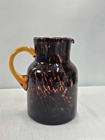 Front view of tortoise shell art glass pitcher showing handle and pattern