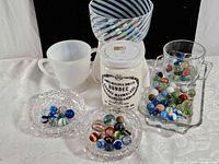 Group shot showing jar, art glass bowl, milk glass mug, crystal dishes, tumbler on tray, marbles