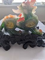 Full view of green and orange dragon statue on black stand