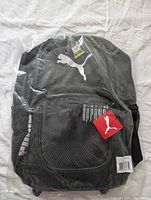 Front view of sealed black Puma backpack with logo and tags