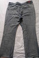 Back view of grey denim jeans laid flat showcasing rear pockets and overall condition