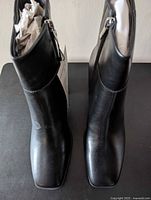 Top view of both black boots showing square toes and inside zippers, paper stuffing inside