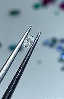 Diamond held in tweezers, showing marquise shape and faceting