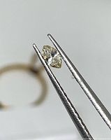 Marquise diamond held by tweezers, side profile visible