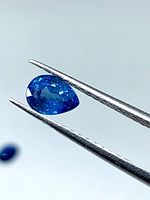 Front view of pear-shape blue sapphire held by tweezers