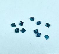 Ten small blue princess-cut diamonds on white background