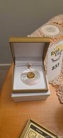 Mother-of-pearl pendant with coin inset displayed in box