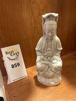 Front view of white porcelain seated monk figurine with lot tag