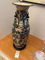 Front view showing full height, battle scene, crackle glaze, dragon handles, wood stand