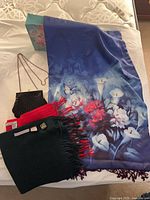 Group shot of silk floral scarf, two cashmere scarves, beaded clutch and decorative box