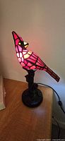 Stained glass cardinal lamp illuminated on table