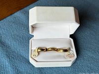 Open ring box showing three gold-filled bands with tags