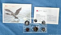 Front view of sealed six-coin set with artwork cover and insert