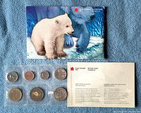 Front view of complete mint set showing seven coins in plastic holder, polar bear sleeve, and information card