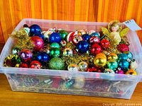 Plastic bin full of assorted vintage glass ornaments, angel, nutcracker and tinsel visible