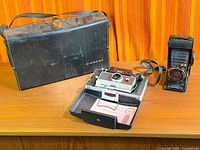 Polaroid 100 Land, Voigtländer Bessa, and Diamond case on table