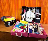 Overall lot: Barbie carry case, two pink trays with clothes, three dolls visible