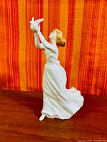 Front angled view of figurine showing woman holding dove, front dress detail