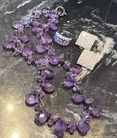 All three items laid out: amethyst necklace, sterling ring, crystal earrings