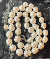 Coiled view of knotted baroque pearl necklace showing extender chain and clasp