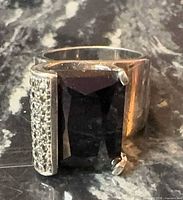 Front view of sterling silver ring showing rectangular black onyx and pavé clear stones