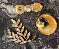 All three brooches displayed on dark marble surface