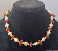 Full view of necklace on display bust showing alternating pearls and amber pieces