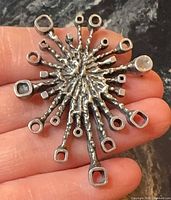 Front view of starburst brooch showing textured spokes and open terminals