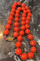 Full view of carved red bead necklace on dark surface