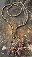 Full view of necklace laid out showing continuous strand and tassel pendant