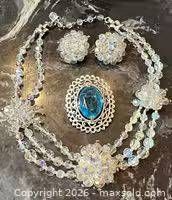 Full view of necklace, earrings, brooch on dark background