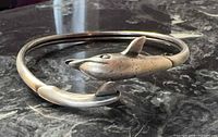 Overall view of sterling silver dolphin bangle showing clasped head and tail