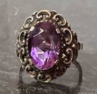 Front view of ornate sterling ring showing oval purple amethyst and scroll bezel