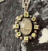 Pendant close-up showing labradorite cabochon, peridot accents and patina