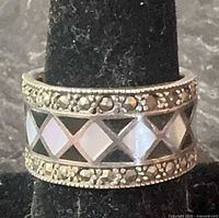 Front view of silver wide band ring showing mother-of-pearl diamond inlay and marcasite borders