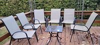 Full set of eight chairs around small glass table on deck