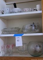 Cupboard showing top, middle and bottom shelves with assorted glass and ceramic items