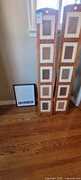Two tall oak-finish frames and one black "Grandkids" frame shown leaning against wall