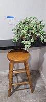 Full view of oak stool beneath shelf with artificial ivy plant basket