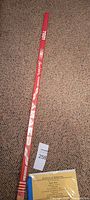 Full length view of red shaft hockey stick on carpet