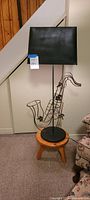 Full view of saxophone lamp with shade on footstool