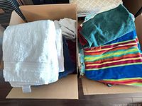 Two cardboard boxes filled with assorted bath, hand, beach towels and washcloths