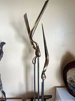 Full view of sculpture showing three main bronze forms on rods