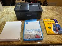 Printer with paper packs and loose paper on countertop