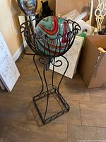 Full view of metal stand with glass ball in basket