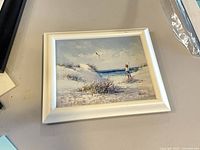 Framed canvas painting on tabletop showing entire artwork and frame