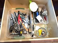 Overview of both clear bins filled with utensils and measuring cup in drawer