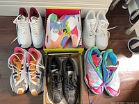 Six pairs of sneakers arranged in two rows, showing colorways and one boxed pair