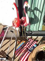 Pair of painted metal flamingos standing beside flags and flag holder