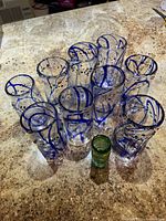 top view of 11 blue swirl tumblers and 1 green shot glass